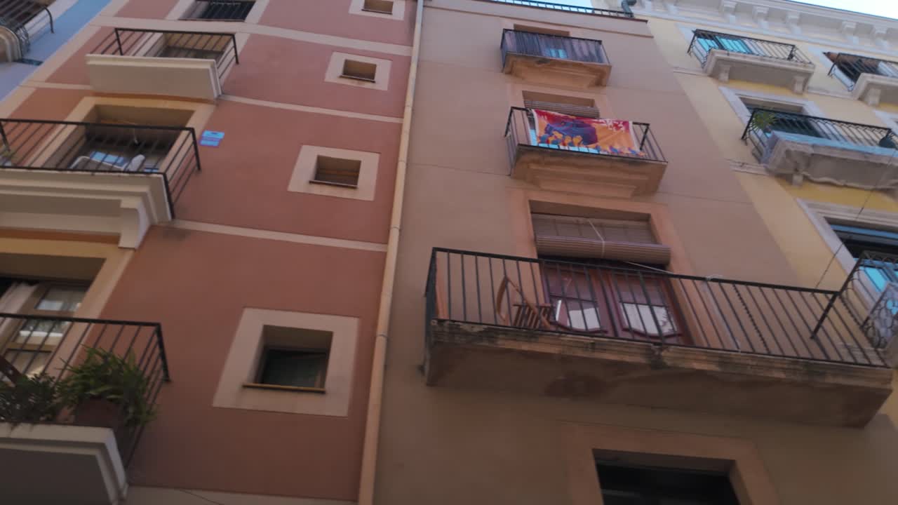 Historic yellow buildings with wrought-iron balconies in a narrow street in Tarragona Spain