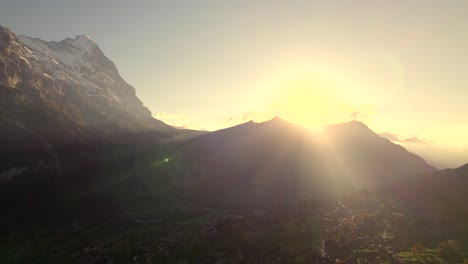 aerial drone footage pushing in over grindelwald with sunset view of eiger north face