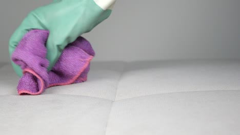 cleaning a light-colored sofa with a cloth