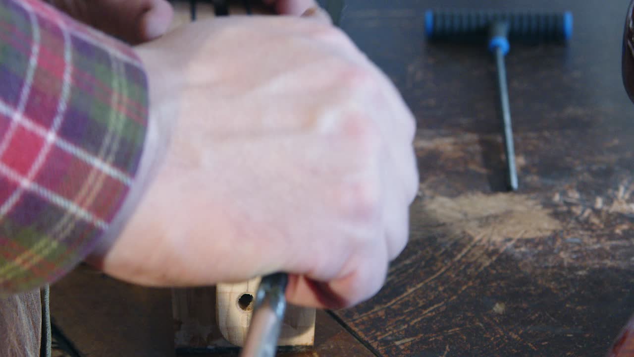 Metal truss rod is removed from wooden guitar neck at luthier work shop
