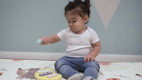 Adorable-toddler-hitting-yellow-musical-toy-while-sitting-on-the-floor