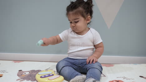 adorable niño golpeando un juguete musical amarillo mientras estaba sentado en el suelo