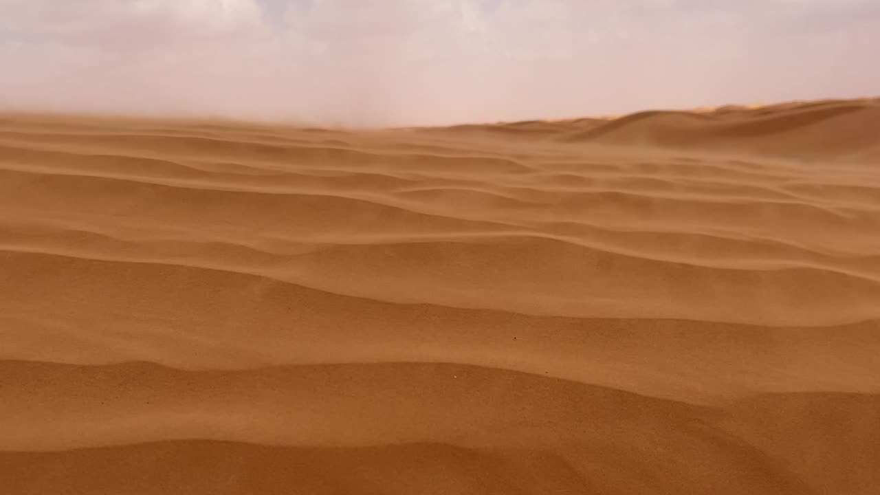 arena soplando sobre la duna del desierto de arena del sáhara en un día ventoso y nublado