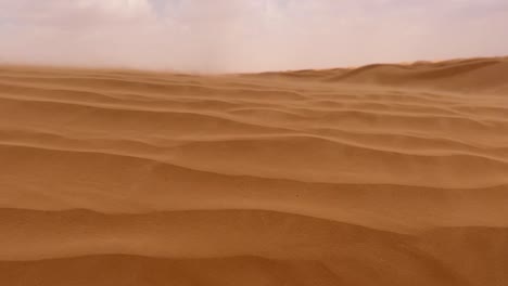 sand blowing over sahara sandy desert dune on windy and cloudy day