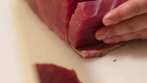 skilled chef slicing a fresh tuna on a chopping board in the kitchen of a japanese restaurant