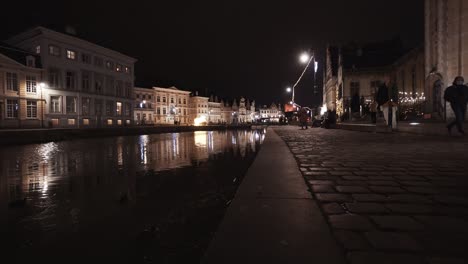 ángulo-Bajo-Estático-De-Graslei-Del-Río-Leie-Con-Reflejo-De-Linterna-En-El-Agua-Y-Korenlei-En-El-Fondo-Durante-La-Noche