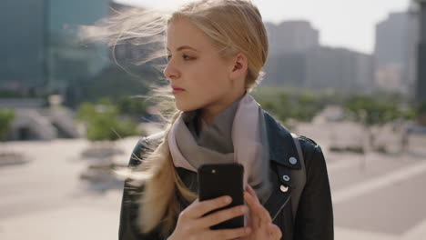 slow-motion-portrait-of-cute-young-blonde-woman-texting-browsing-using-smartphone-social-media-app-in-windy-urban-city-background