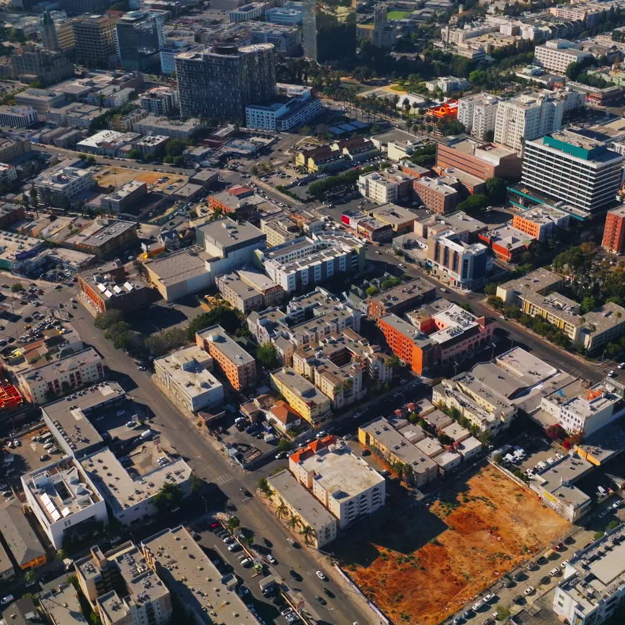 Numerous cars moving by the streets of sunny Los Angeles, California, USA. Diverse architecture of the city and park from top view