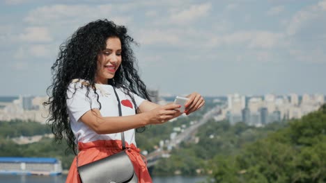 una chica hermosa hace una selfie en el fondo de la ciudad y envía un beso aéreo