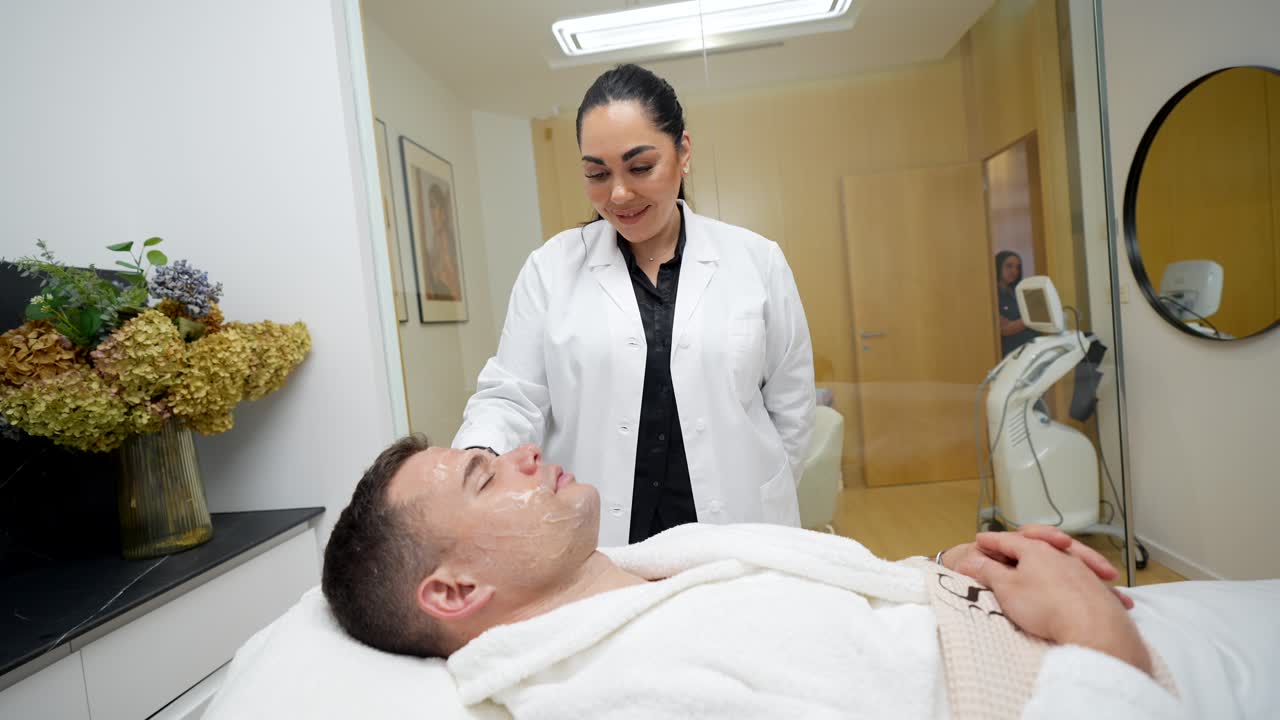 Mann erhält Gesichtsbehandlung von Kosmetikerin in modernem Spa.
