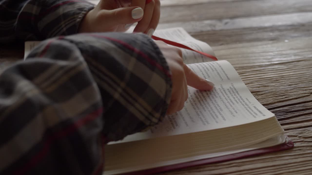 Female finger following holy bible scripture passage reflecting on the word of god