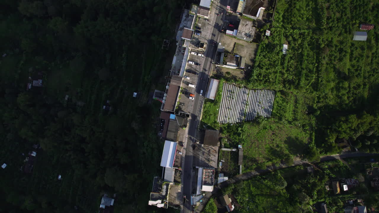 Aerial view of a town with a road and buildings surrounded by trees and vegetation