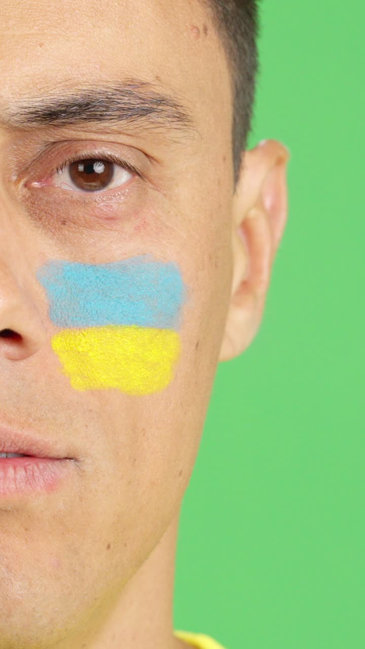 Man with a ukrainian flag painted on the face smiling