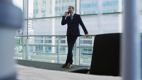 Businessman-on-smartphone-in-modern-office-building