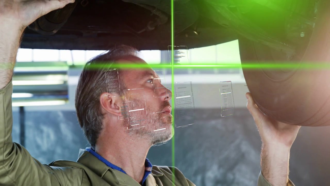 Técnico automotivo levanta roda acima da cabeça, ativando escaneamento a laser verde para alinhamento.