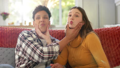 happy diverse couple sitting on sofa having video call at home, in slow motion