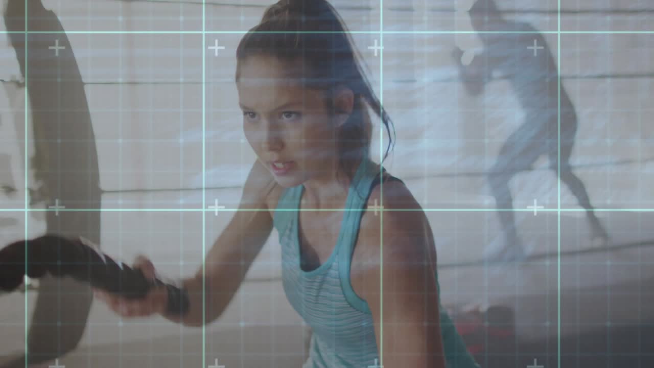 Woman gripping battle rope starting alternating waves for strength in gym HUD grid overlay tracking