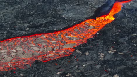 Aerial-close-up-view-of-lava-stream-textures,-coming-from-the-volcanic-eruptions-at-Litli-Hrutur,-Iceland,-with-smoke-coming-up