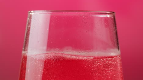 primer plano de una bebida rosada espumosa en una copa de vino
