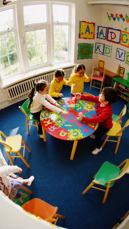 children engaged in alphabet puzzle play in a bright classroom