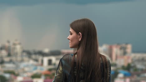 mujer con cabello largo y suelto posa para la cámara contra la ciudad