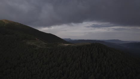 this drone video captures a stunning frontal descriptive shot over the hecho valley, flying past a high mountain refuge with majestic peaks in the background under a dramatic cloudy sunset.