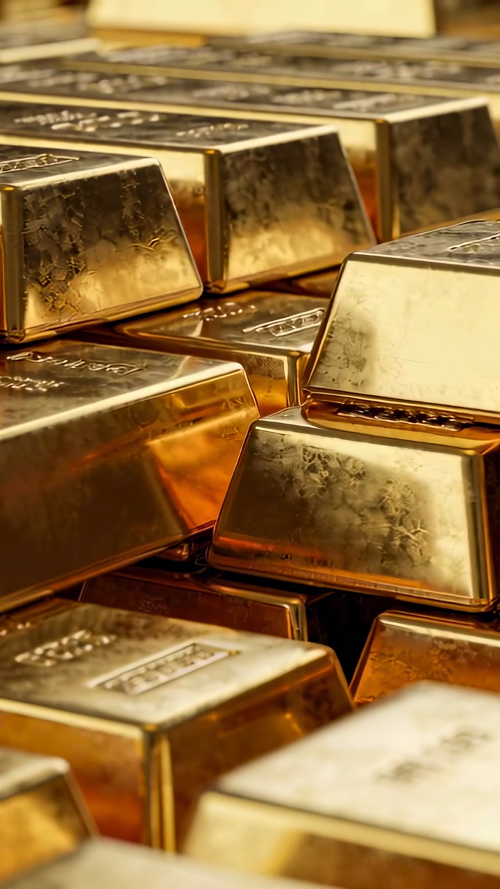Vertical video: Shifting camera revealing stacked gold bars in vault, exposing stamps and scratches