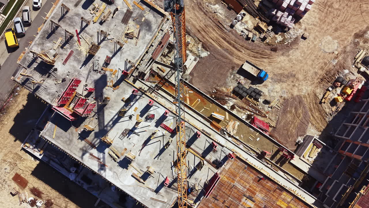 Construction workers are building a new structure at a construction site in a city during daytime hours as a crane lifts materials overhead