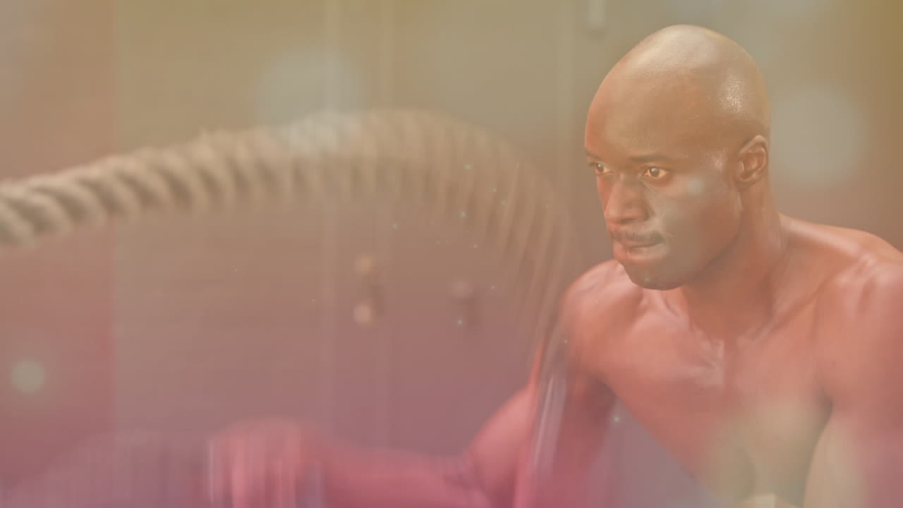Animation of glowing light over fit man exercising in gym
