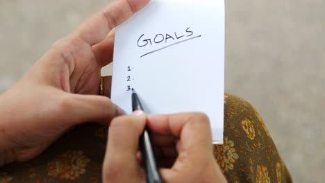 person writing goals on a notepad