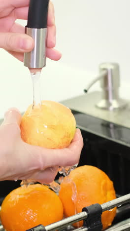 hands washing an apple under running water in a kitchen sink