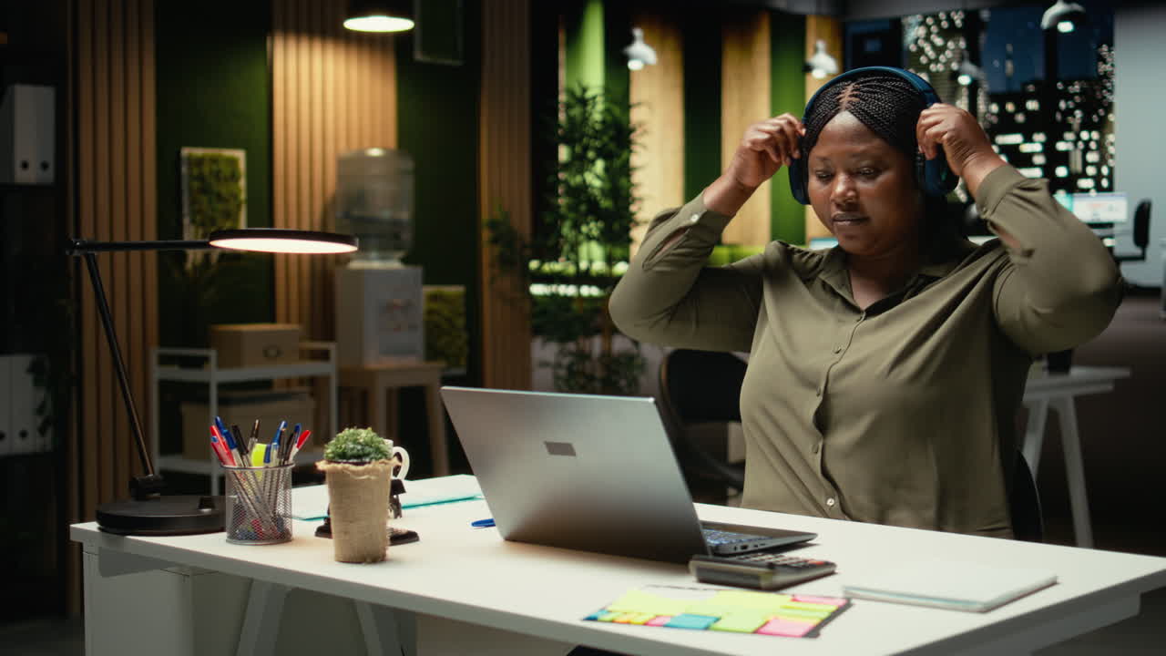 Black woman listening to focus music on headphones at the office
