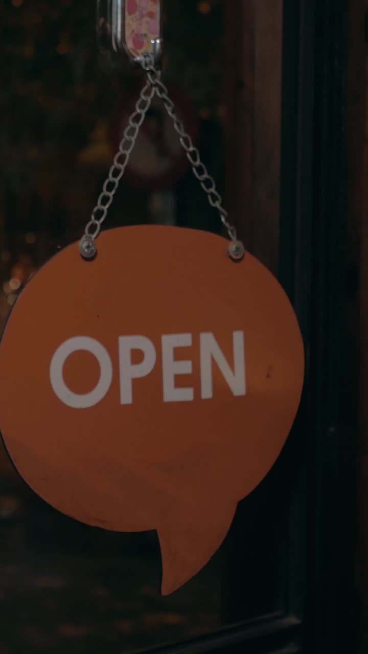 Hands Flipping a "Close" Sign to "Open" on a Glass Door
