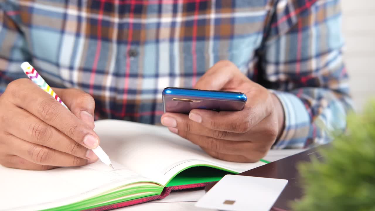 persona que toma notas y utiliza un teléfono inteligente