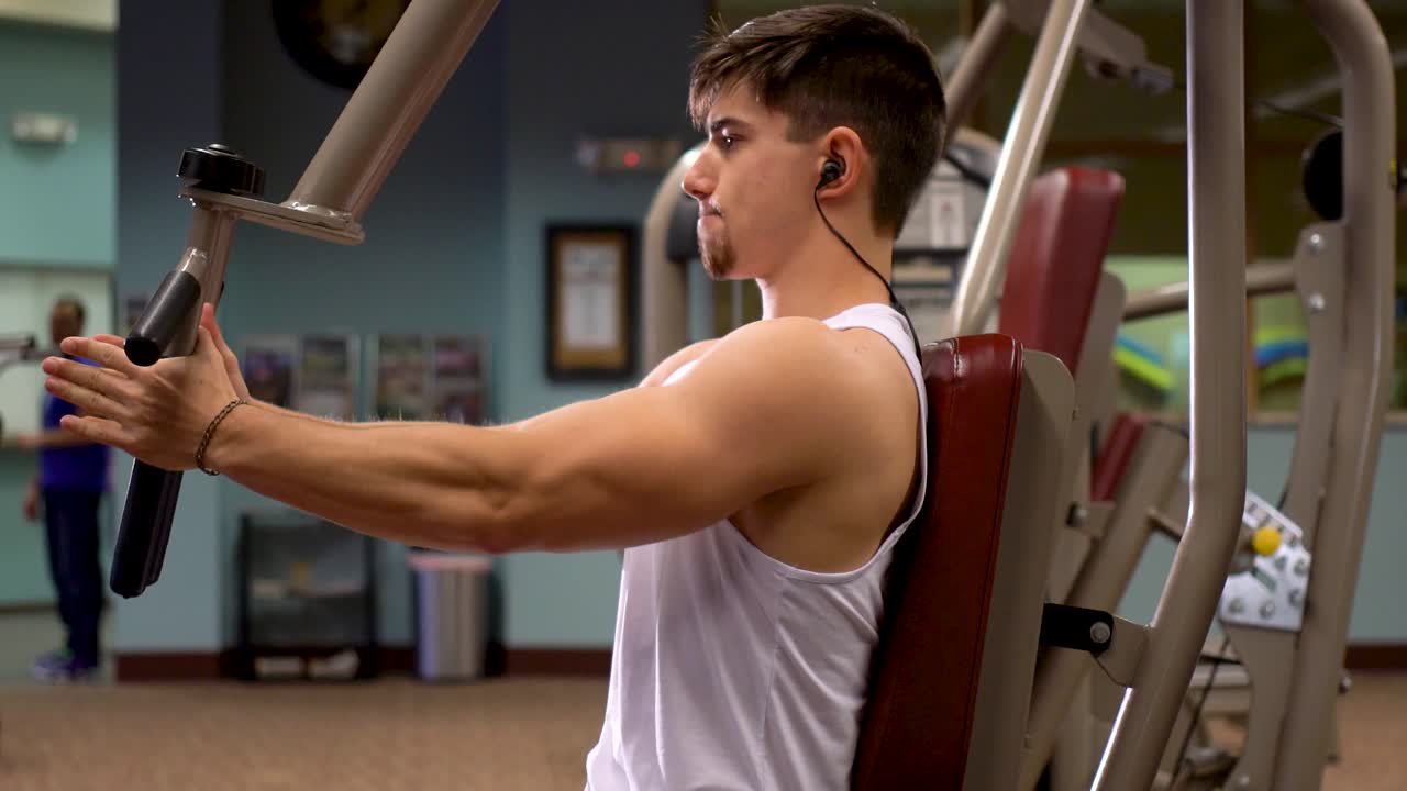 primer plano de un joven culturista trabajando el pec dec en un gimnasio