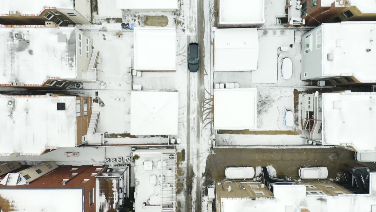 Aerial, car drives through urban alley after winter snow storm