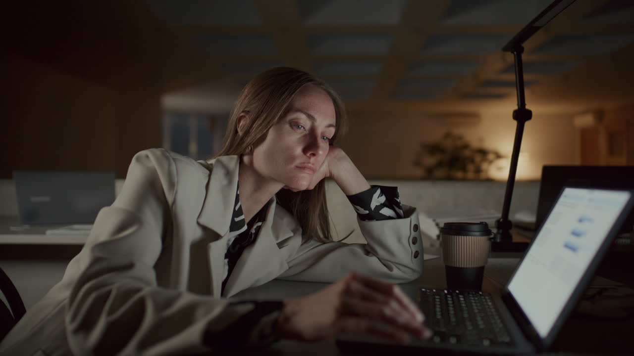 Tired Woman Working Late on Laptop and Writing Notes in Office at Night