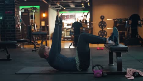 caucasian man exercises on a yoga mat at gym. male fitness model performing abs crunch at fitness center - side view