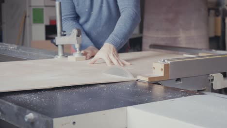 carpintero cortando una hoja de madera contrachapada con una sierra de mesa