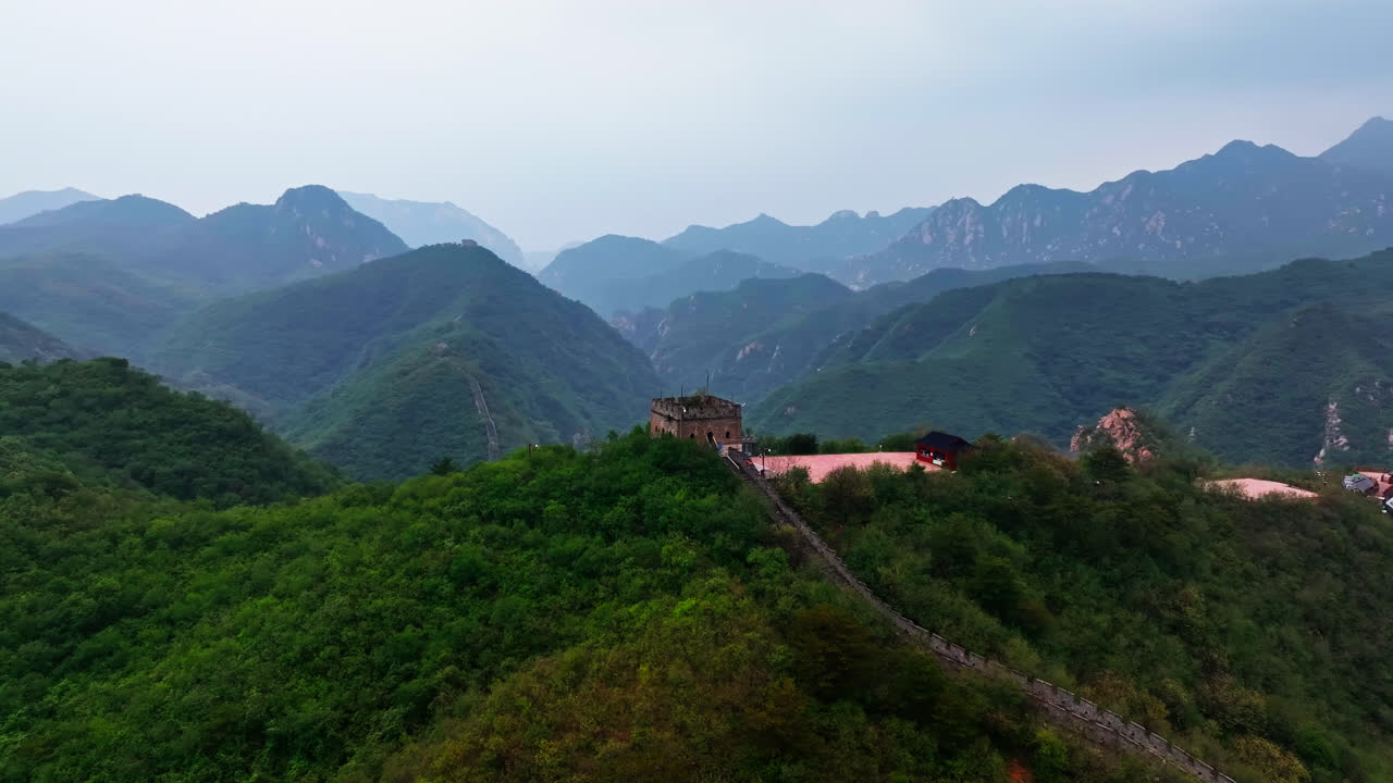 Panoramic drone shot around a hilltop watchtower at the Great Wall, in cloudy China