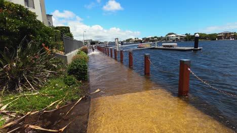 a wake of water behind a bike rider that pushes through a flooded pathway during high tide