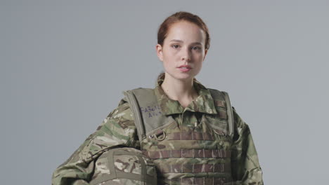 Retrato-De-Estudio-De-Una-Joven-Soldado-Seria-Con-Uniforme-Militar-Sobre-Fondo-Liso