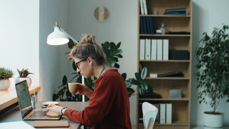 Mujer-De-Negocios-Usando-Laptop-Y-Tomando-Café-En-La-Oficina