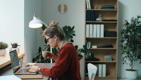 businesswoman using laptop and drinking coffee in office