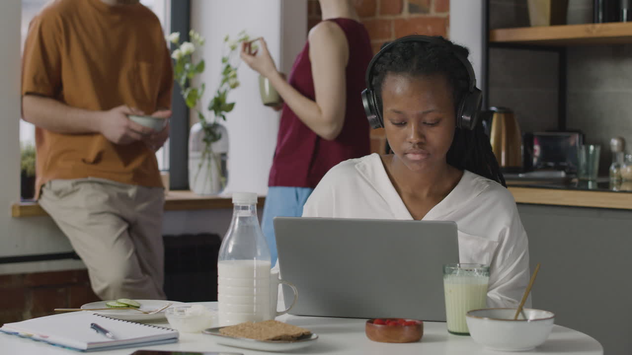 Girl With Headphones Having Breakfast And Working On Laptop Computer In A Shared Flat 2