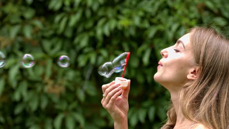 a teenage lady making bubble with a blow and watch them in the air