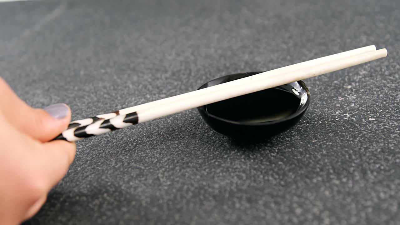 Chopsticks and soy sauce on black stone slate