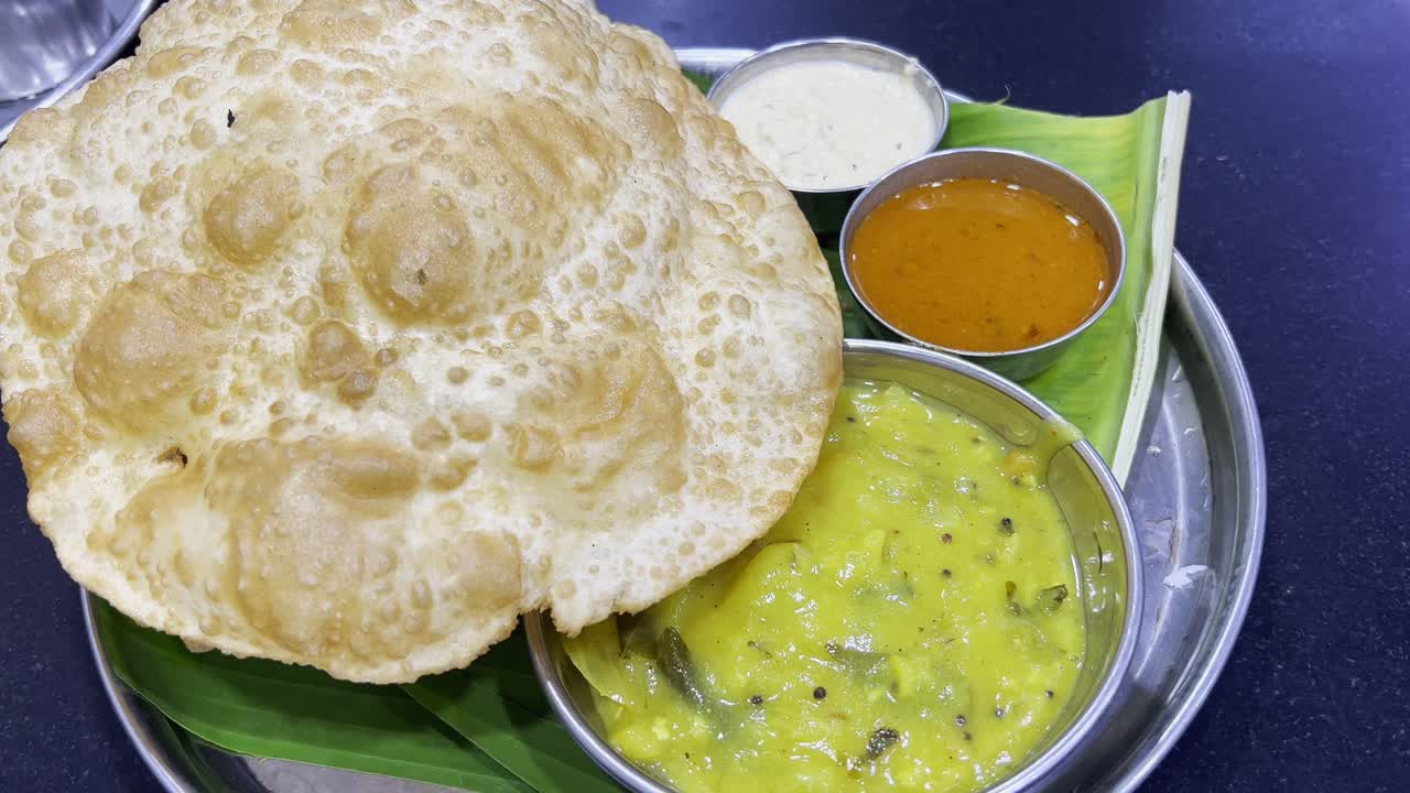 toma estática de un delicioso plato de comida india que consiste en puri, sabji, dal y chutney
