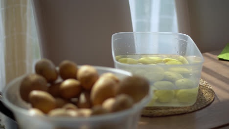 papas sin pelar y peladas en recipientes separados