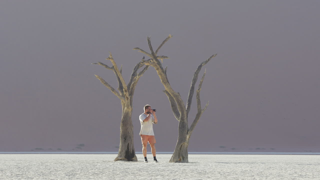 fotógrafo con cámara tomando fotos en deadvlei, cacerola de arcilla en sossusvlei